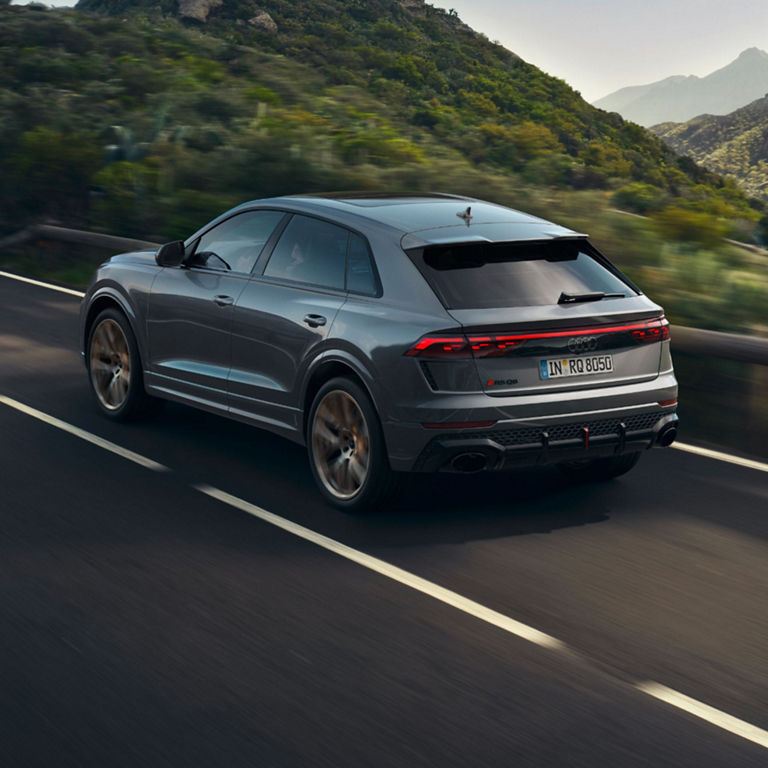 Dark grey Audi RS Q8 driving up a mountainside road.