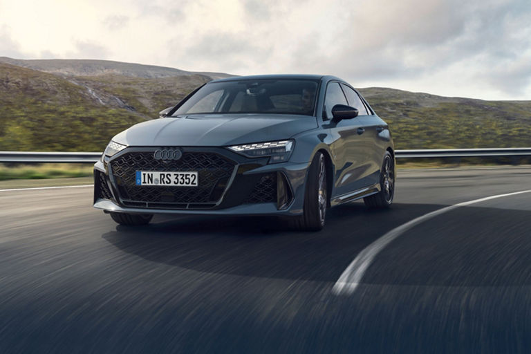Audi RS3 driving on a highway with mountains in the background.