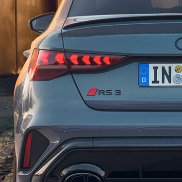 Rear view of a silver Audi RS3 Saloon with distinctive taillights and dual exhaust, parked outdoors.