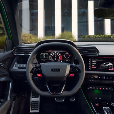 Interior view of an Audi vehicle focusing on the steering wheel and dashboard displays.
