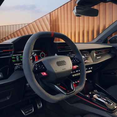Interior of an Audi car showcasing steering wheel and dashboard at sunset.