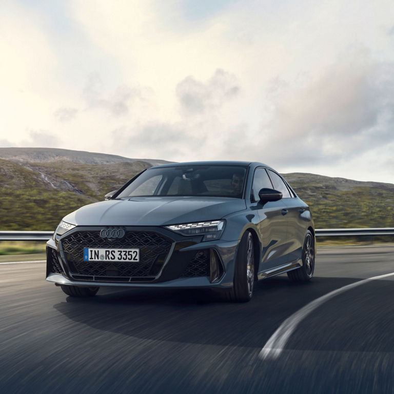 Audi RS3 Saloon driving on a highway with a mountainous background.