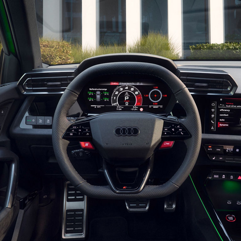 Interior view of an Audi car showing the steering wheel, digital dashboard, and center console.