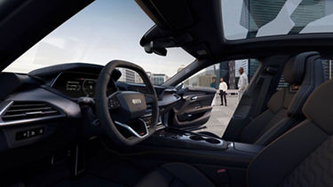 Interior view of Audi car with dashboard and steering wheel, overlooking a cityscape.