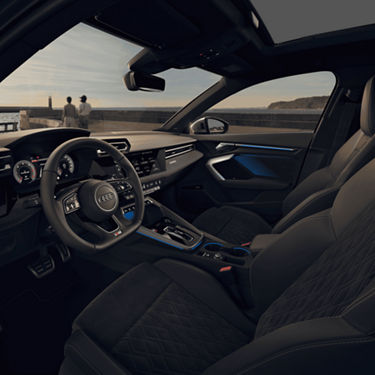 Interior view of a Audi car with leather seats and a view of people by the sea through the windshield.