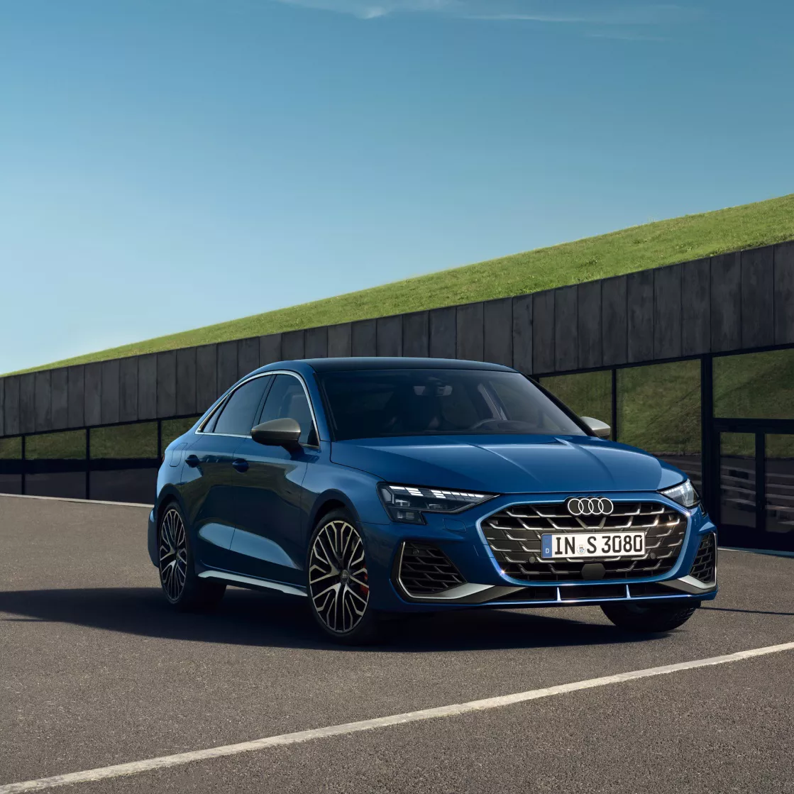 A blue Audi car parked outdoors with clear skies in the background.