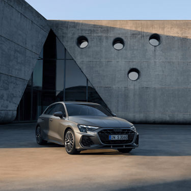  A modern Audi S3 Sportback car parked in front of a building with circular windows.