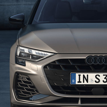  Close-up of a gold Audi S3's front grille and headlights.