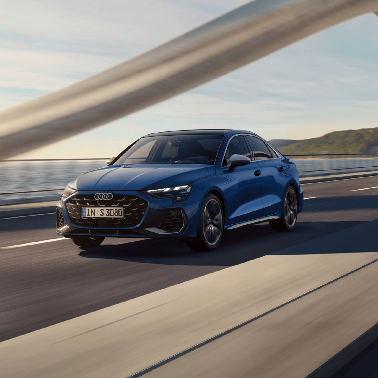 Blue Audi S3 Sportback car driving on highway with scenic ocean backdrop.