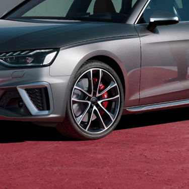 Close-up of a silver car's front wheel and headlight, showcasing a sporty alloy rim design.