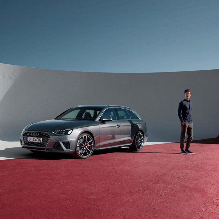 A silver car on a red floor with a person standing beside it.