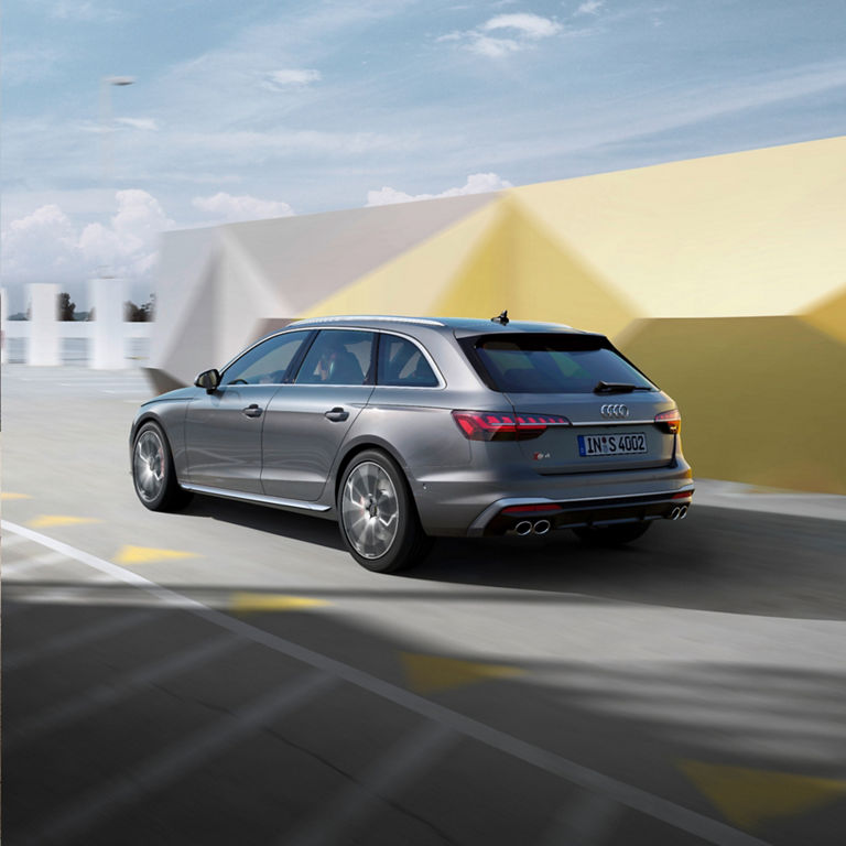 A silver Audi car driving quickly on an urban road with motion blur background.