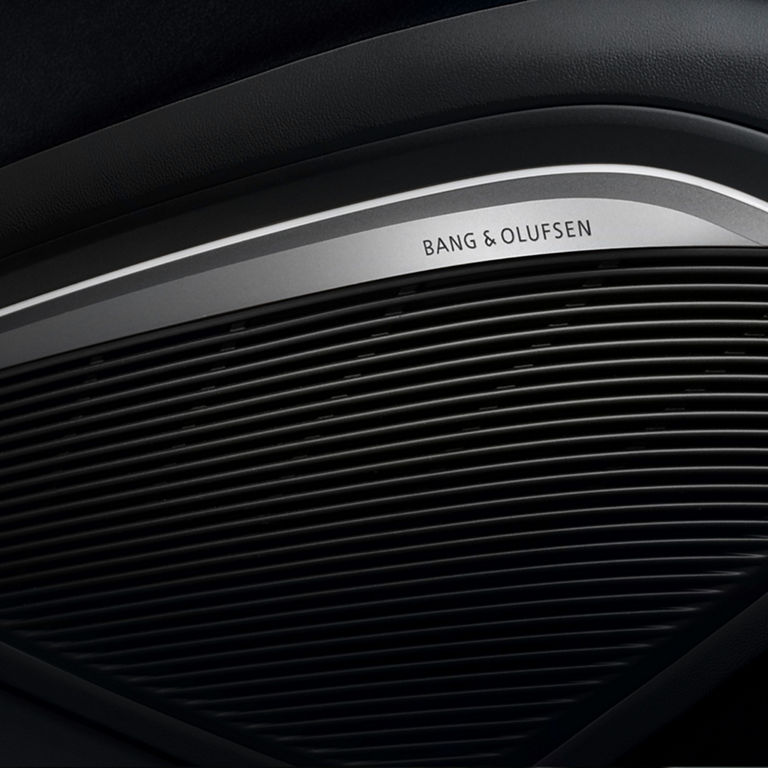 Close-up of a Bang & Olufsen speaker grille in a car interior.