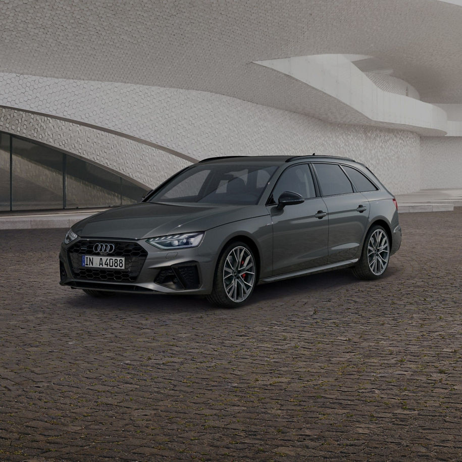 A grey car parked in front of a modern textured building facade.