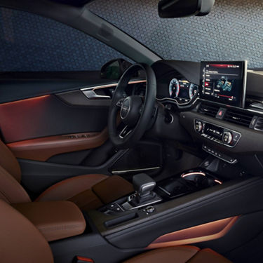 Car's interior with leather seats, dashboard with touchscreen, and steering wheel.