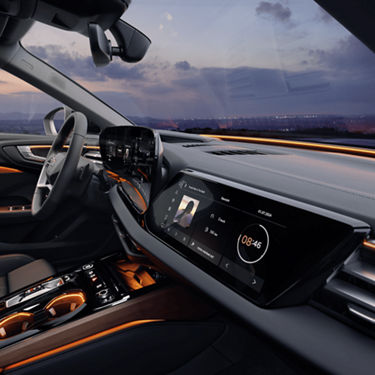 Audi car interior with steering wheel and dual dashboard screens at dusk.