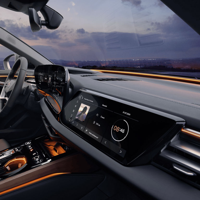 Car interior at dusk with dashboard, steering wheel, and touchscreen display.