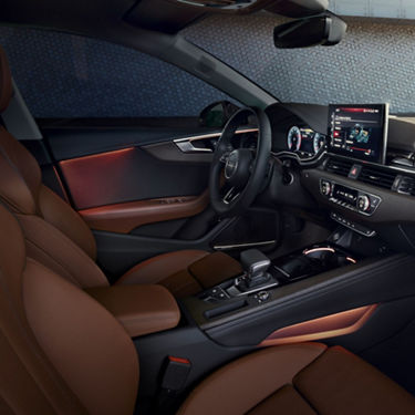 Interior of a car with brown leather seats, dashboard controls, and infotainment system.