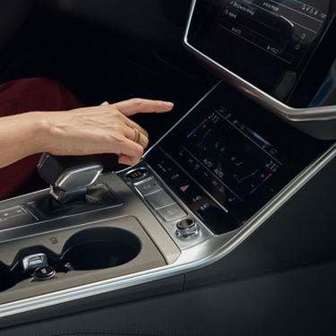 A person's hand adjusting settings on a car's touchscreen console.