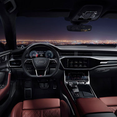 Interior view of a car with leather seats and dashboard screens at night.