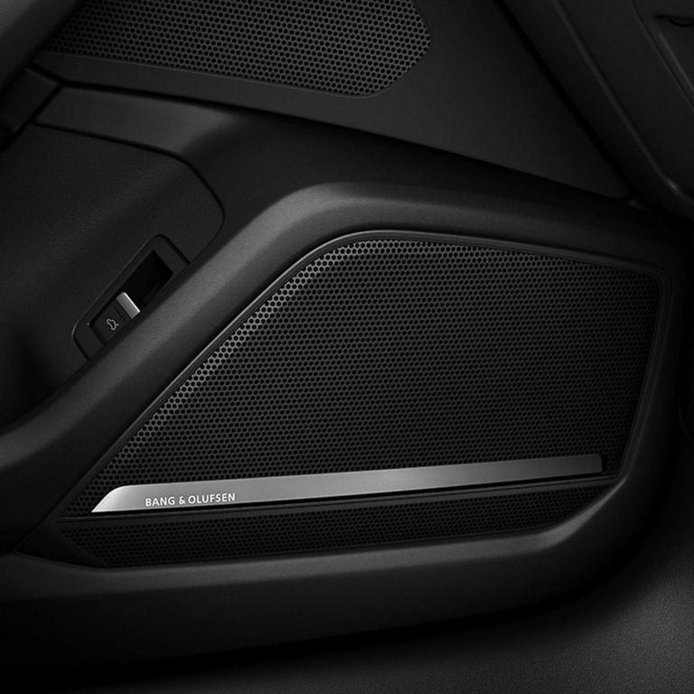 Close-up of a car's speaker grille with "Bang & Olufsen" branding on a sleek black panel. 