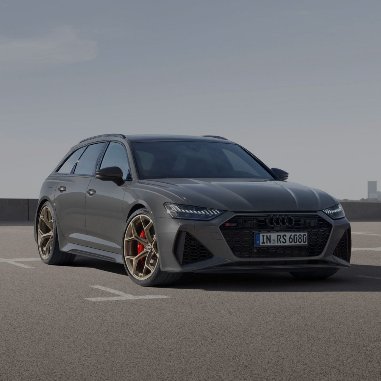 A grey Audi RS6 Avant performance on a tarmac with a clear sky in the background.