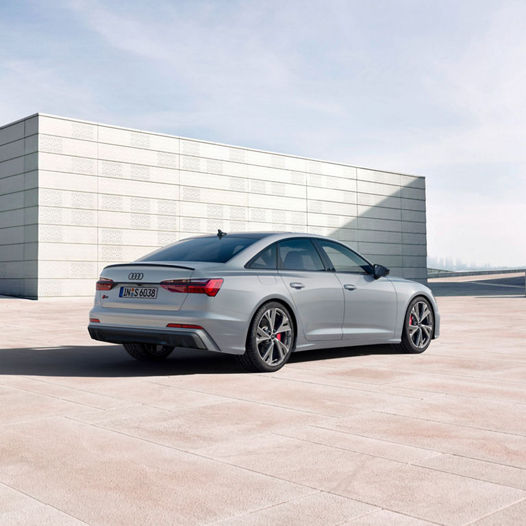 A silver sedan parked outdoors with a modern building backdrop.