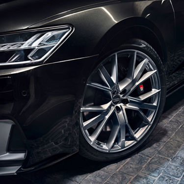 Close-up of a black Audi car's front wheel and headlight.