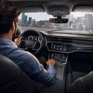 Person driving a car with a sleek dashboard and touch controls.