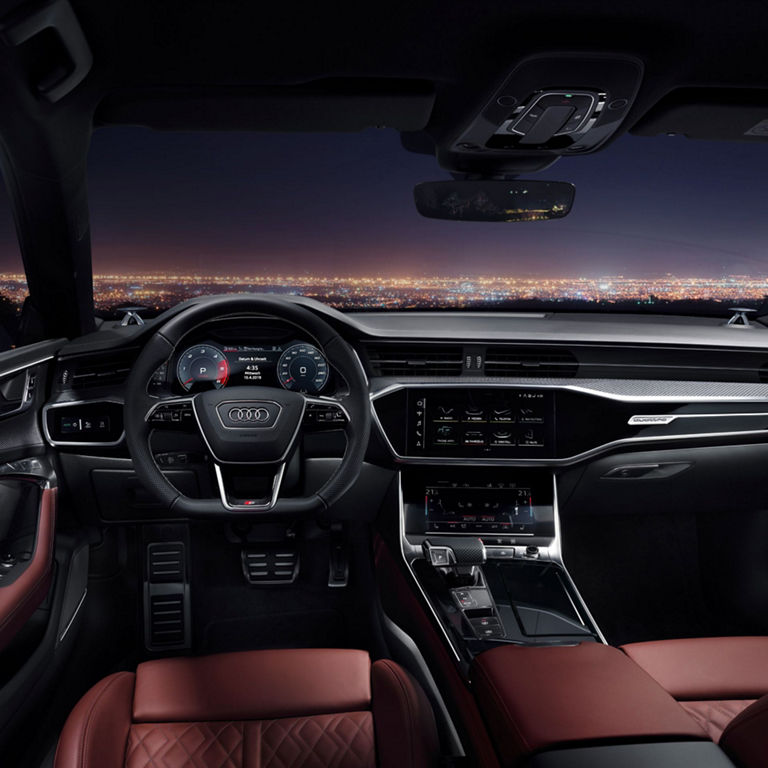 Interior view of a car with red leather seats and dashboard displays at night.