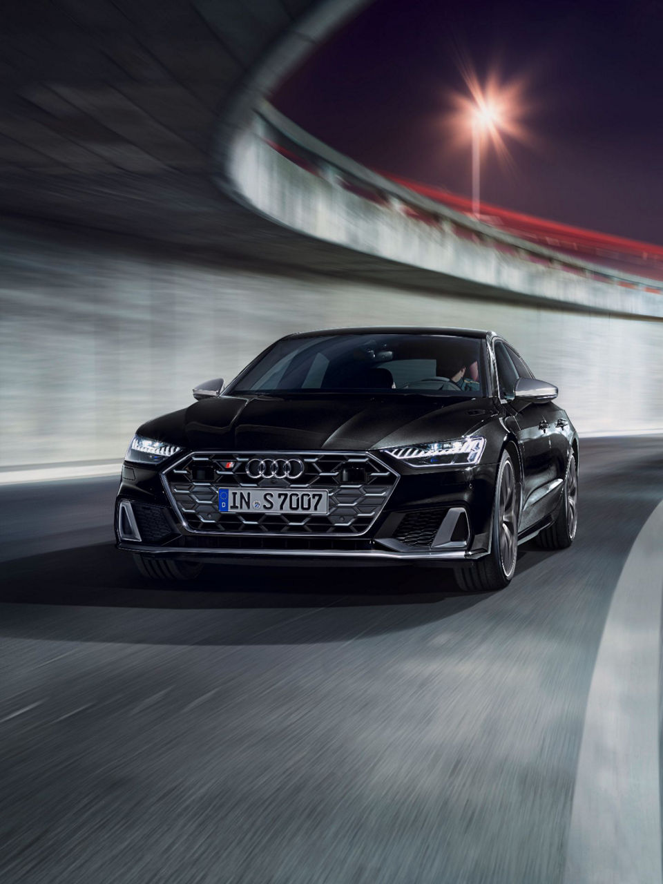A black Audi car driving on a curved road with motion blur.