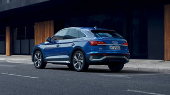 Blue Audi Q5 Sportback SUV parked outside a modern building.