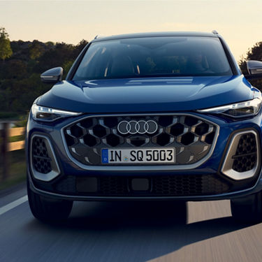 A blue Audi SUV in motion on a road during daytime.