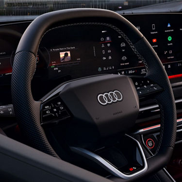 Interior view of an Audi car with steering wheel and digital dashboard displays.