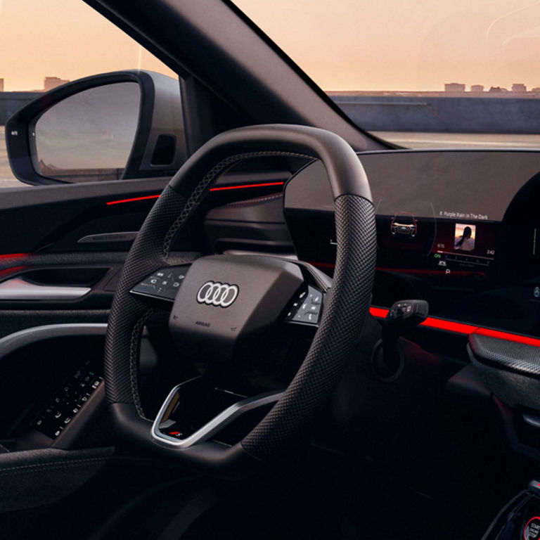 Interior of an Audi with a steering wheel and curved digital display.