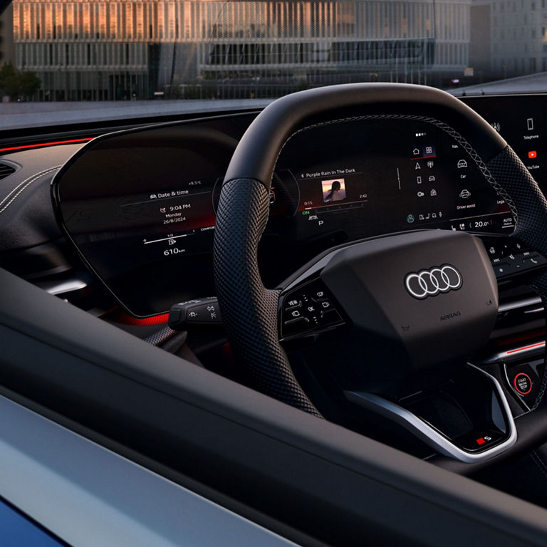 Interior of a car with digital dashboard displays and a steering wheel with logo.