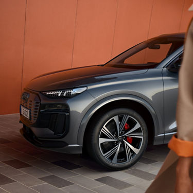 Front angle of an Audi electric SUV parked against a red wall.