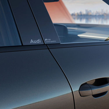 Close-up view of an Audi SQ6 e-tron with city skyline reflection.