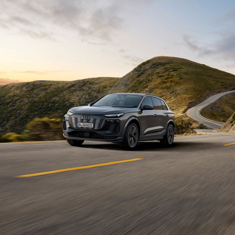 A SUV driving along a winding road with mountains in the background.