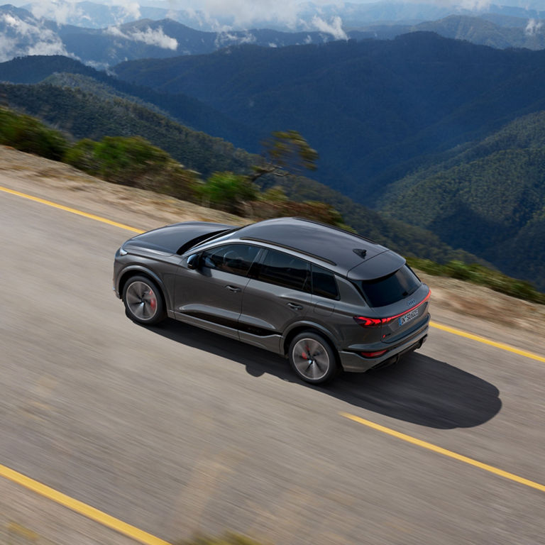 A grey SUV driving on a mountain road with scenic views.