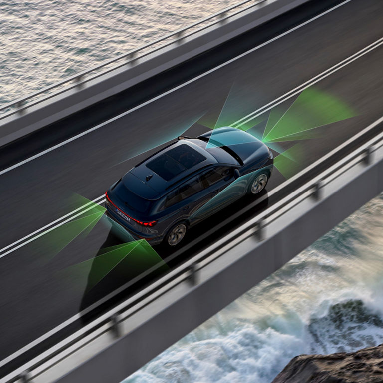 A blue car with dynamic graphics illustrating its sensors on a coastal bridge.