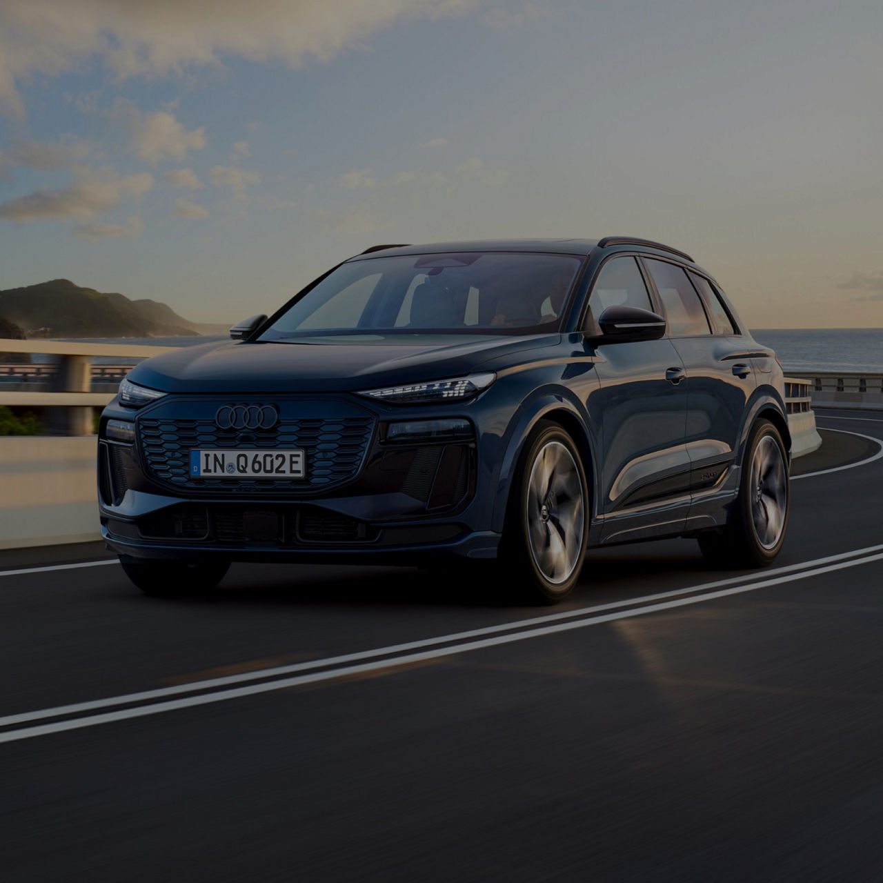 Audi Q6 SUV e-tron moving along coastal road.