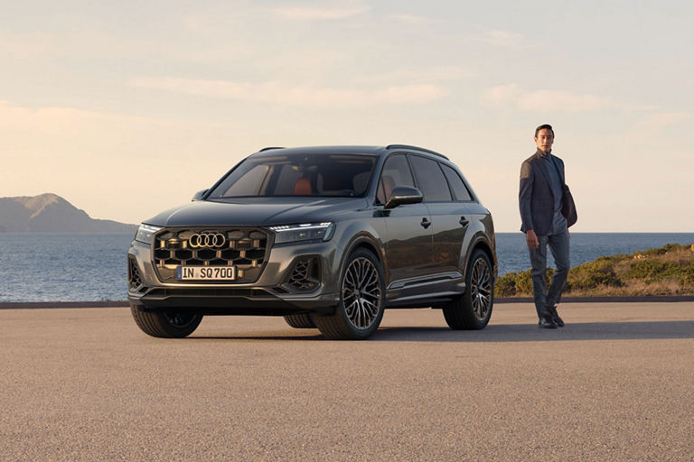 Audi SUV parked by the seaside with a man standing beside it.