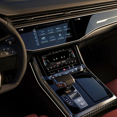 Car interior with dual touchscreen controls and a gear shift.