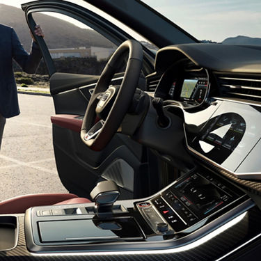 Interior view of a car with an open driver's door and visible infotainment system.