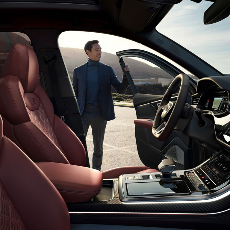 Car interior with red leather seats and open driver's door.