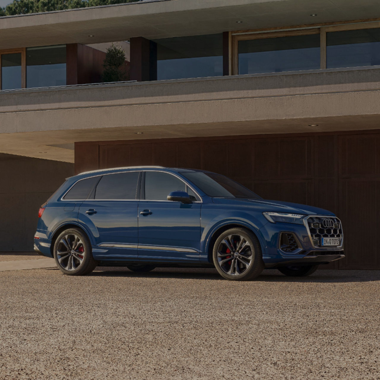 A blue SUV parked in front of a modern house with a concrete facade.