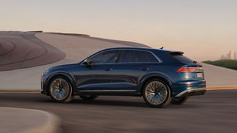 A blue SUV in motion on a smooth desert road with blurred background.