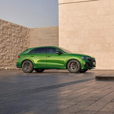  Sport green Audi parked near modern wall on tiled pavement.