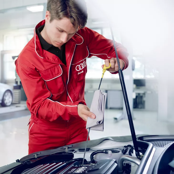 An Audi technician checking the oil from the engine of an Audi vehicle